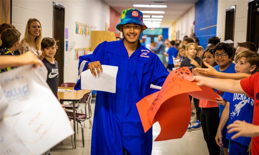 A senior wearing a graduation robe takes signs encouragement